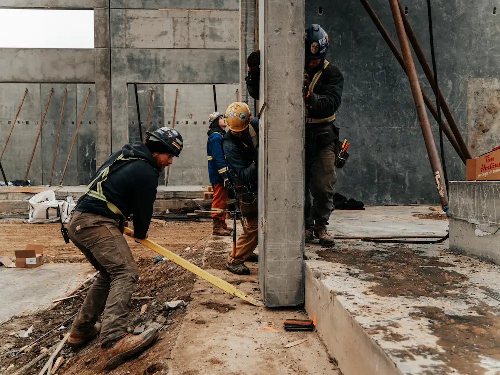 Concrete workers pushing wall up into foundation