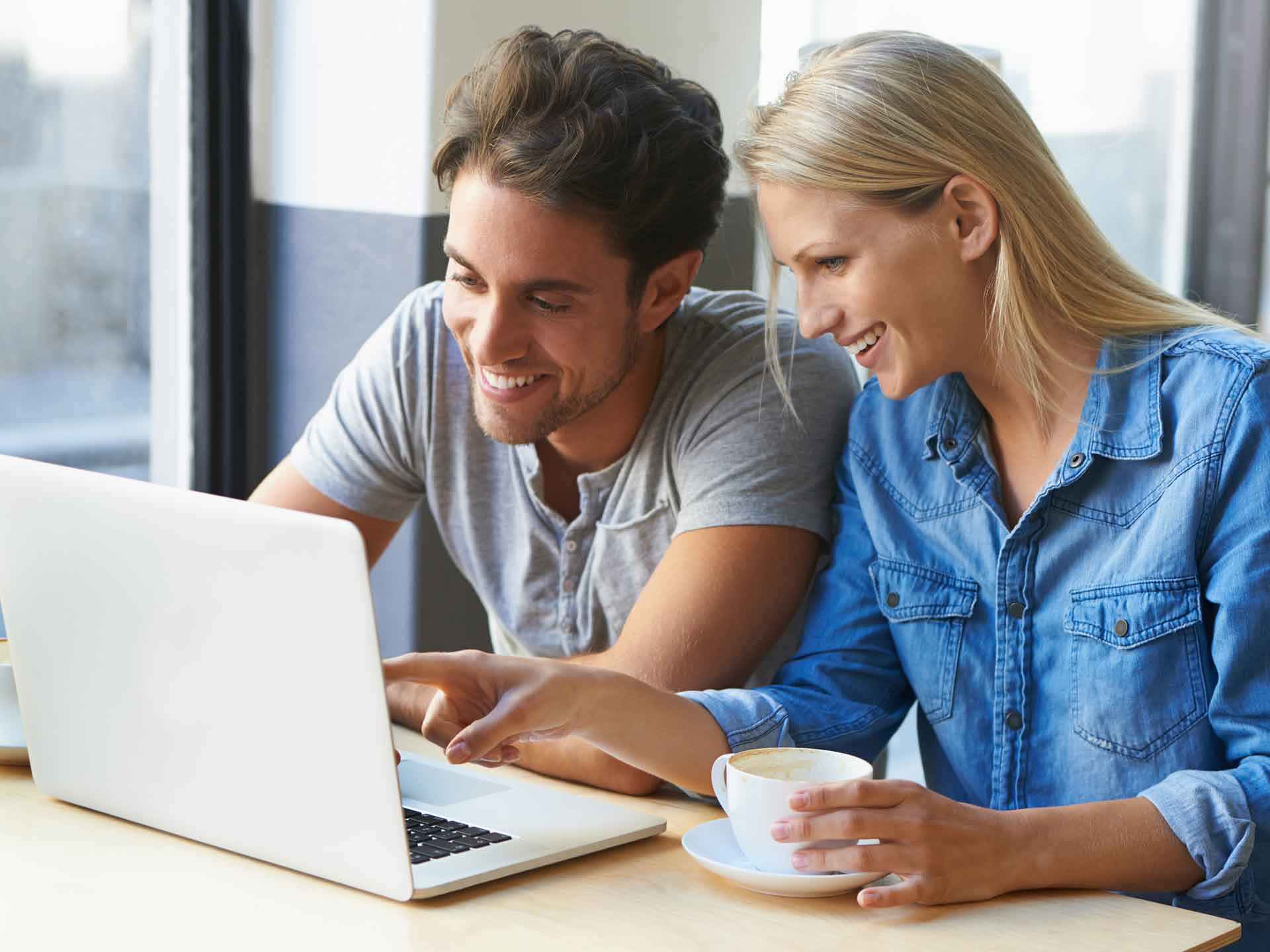 Couple looking at a laptop together over coffee