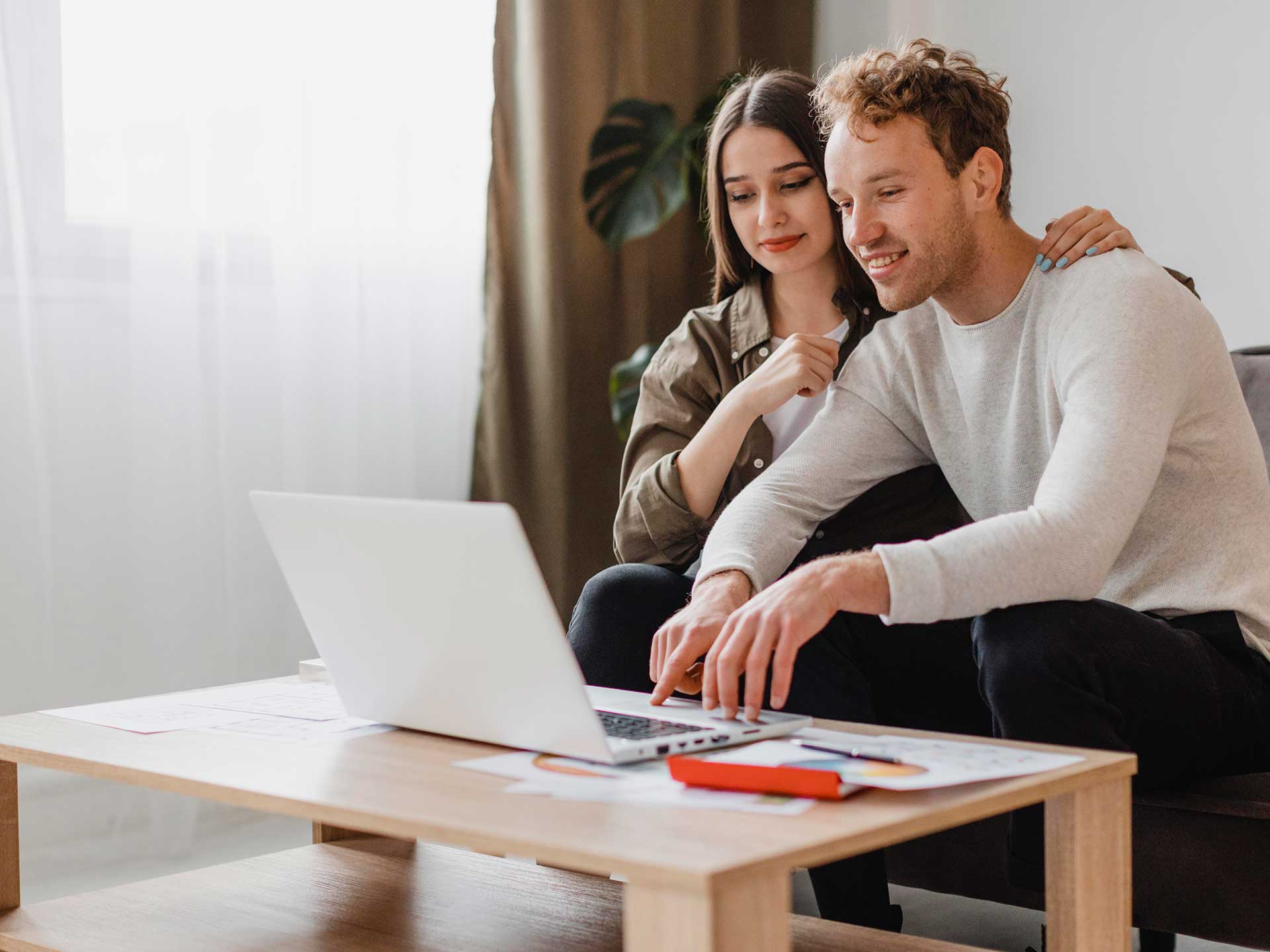 Couple looking at a laptop on a coffee table at home
