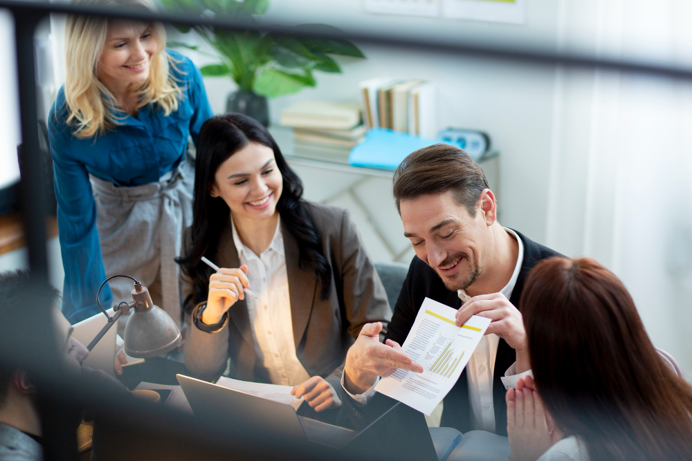 Colleagues gathered around a desk reviewing a document together