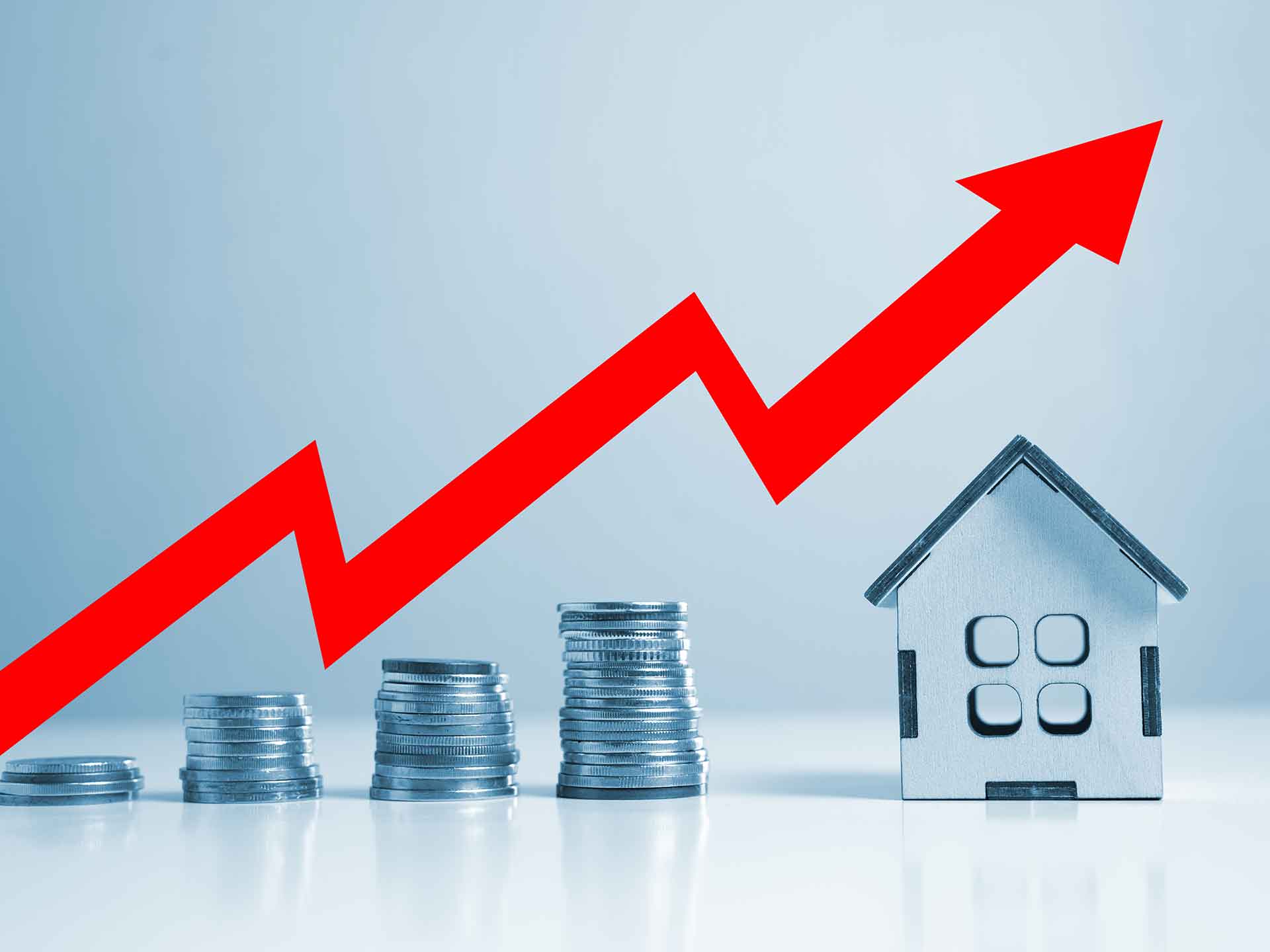 Red upward arrow above stacks of coins beside a model house