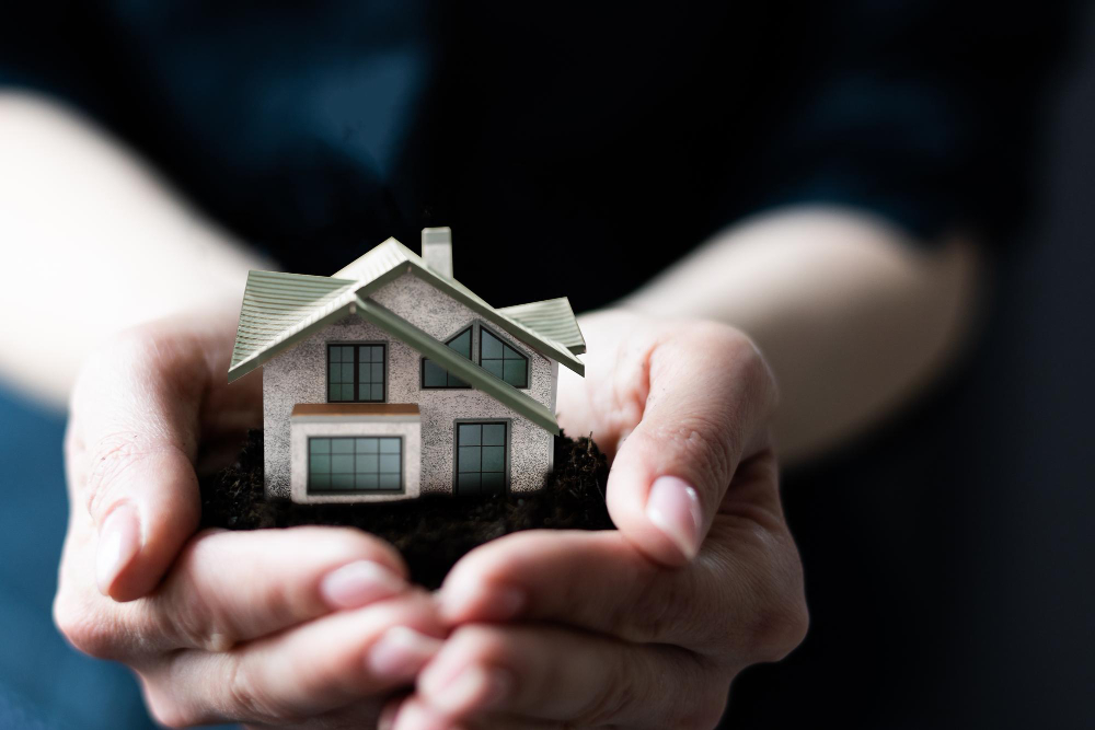 Cupped hands holding a small model house