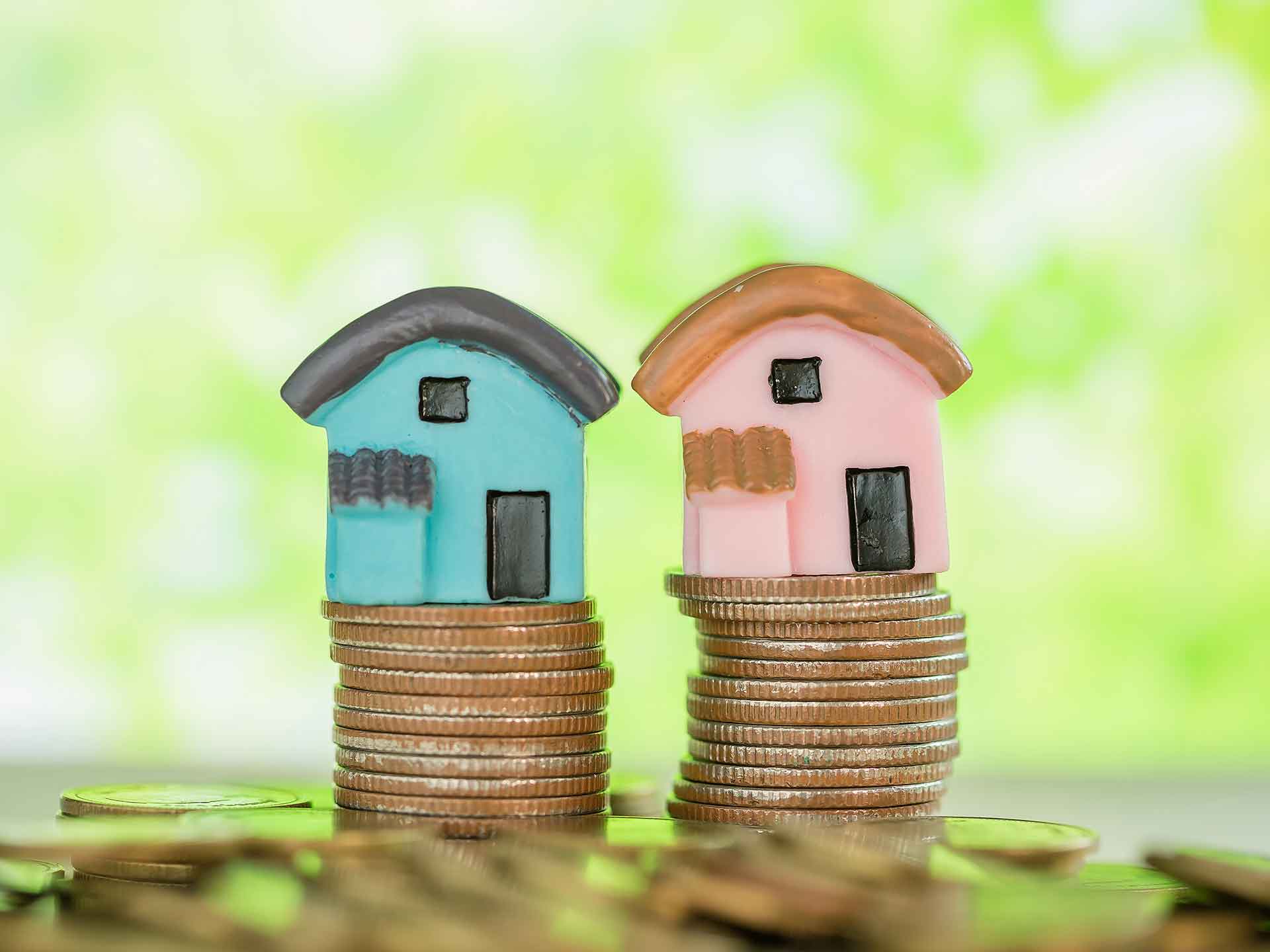 Two model houses sitting on stacks of coins