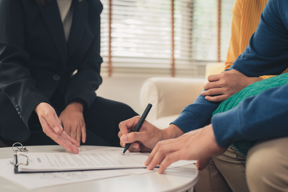 Two people signing a document across a table