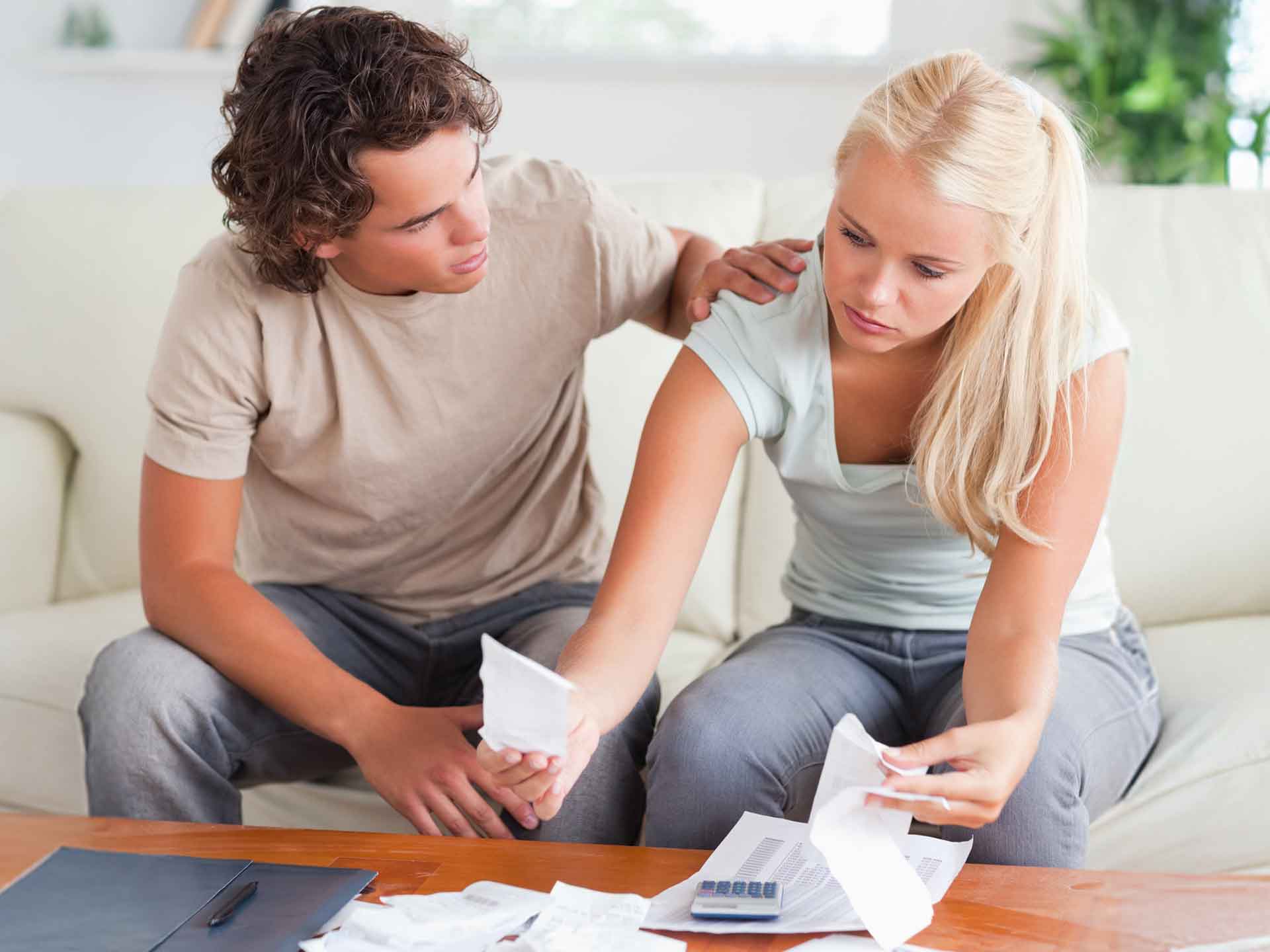Couple going through paperwork with a calculator at home