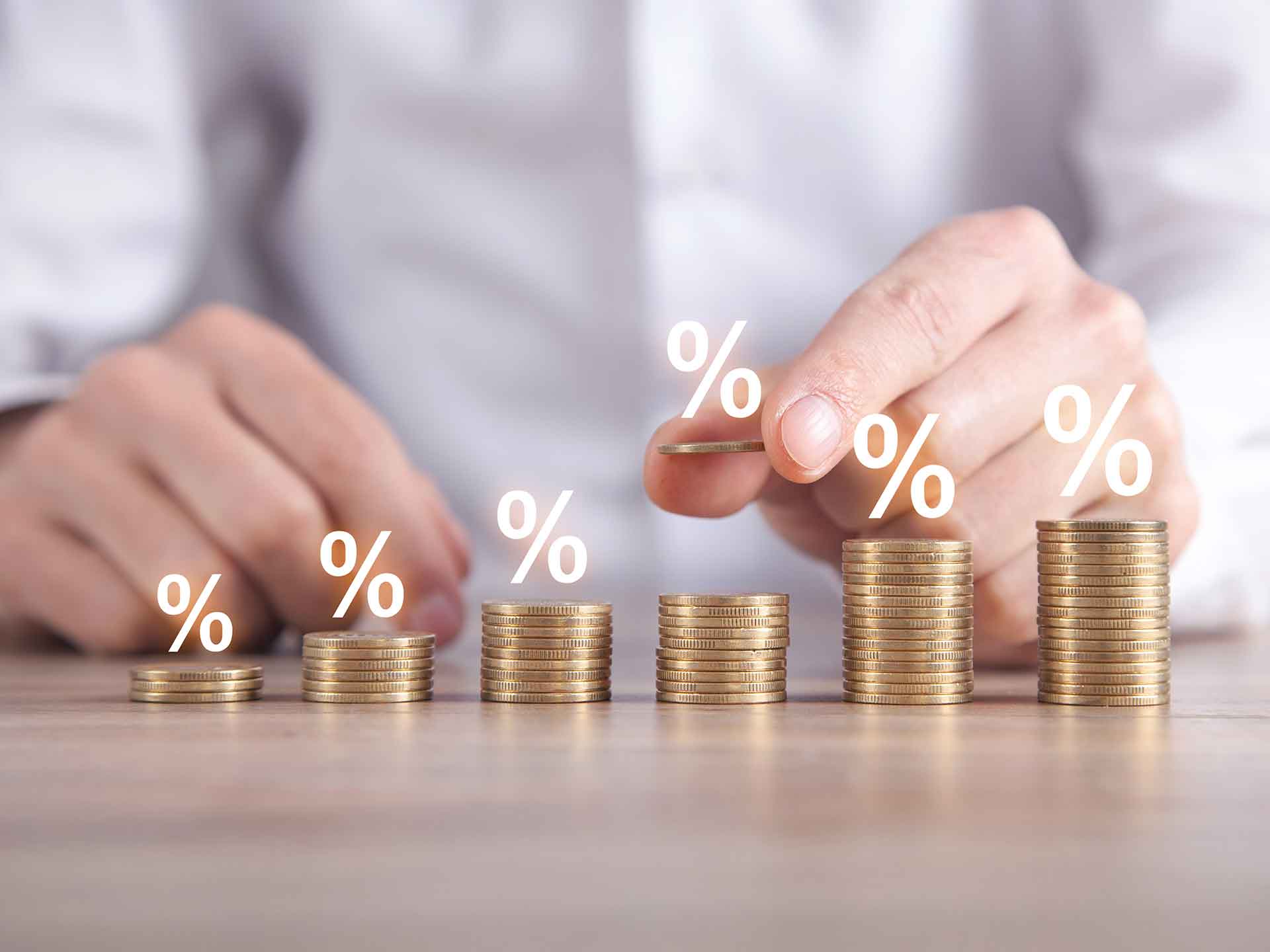 Hand stacking coins with percentage symbols floating above them