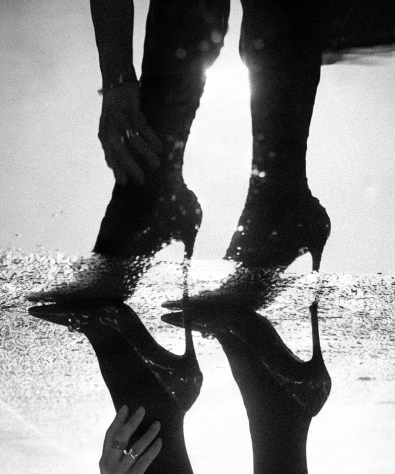 Black heeled boots and a hand reflected in water, shown from a low angle in the generated image.