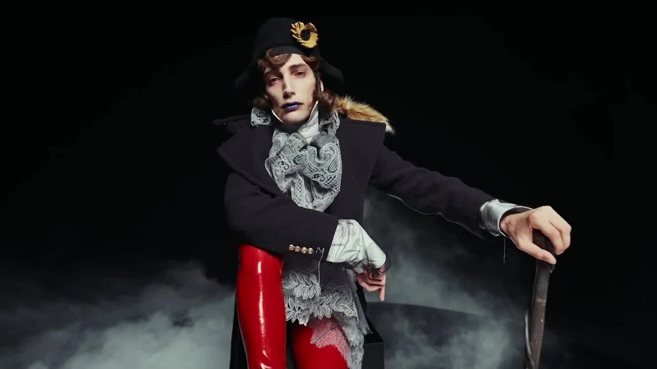 A character in red boots performs within the film’s dark, mist-filled set.