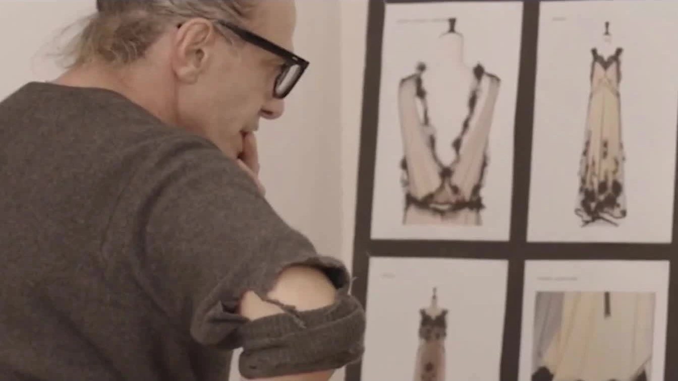 Couturier John Galliano working with collection drawings.