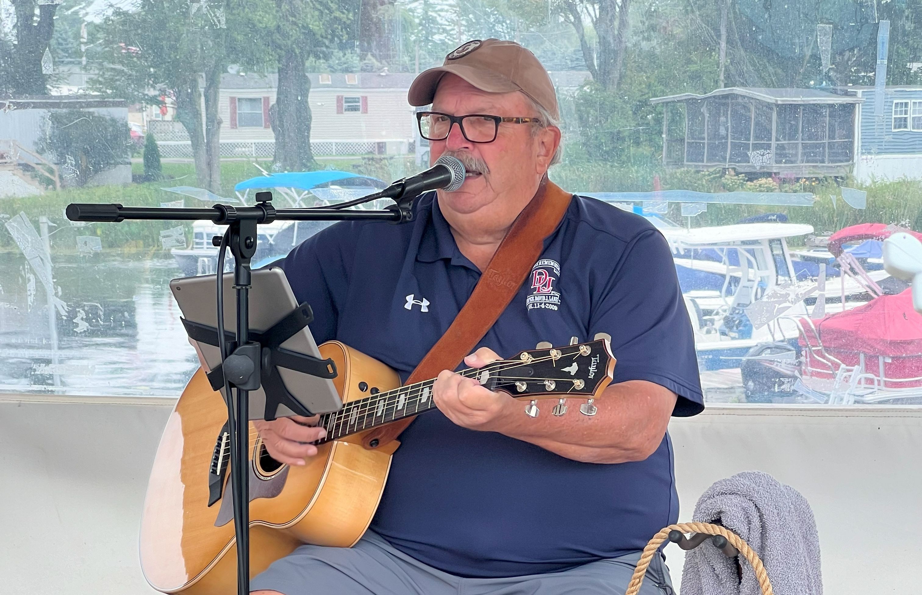 Bill Burkhard performs live at Why Knot Tiki Bar. An outdoor stage with water in the background, May 25, 2025.