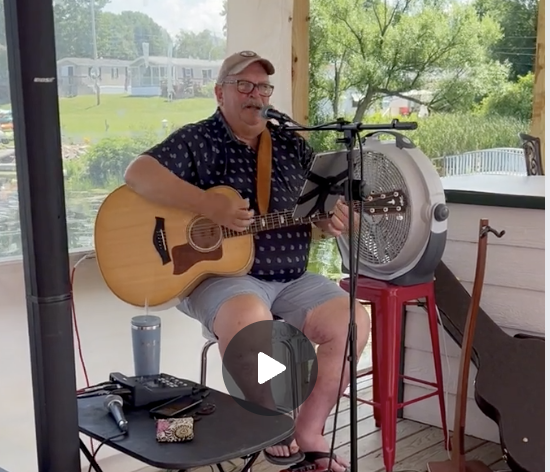 Bill Burkhard performing live at the Why Knot Tiki Bar, June 2025, with a vibrant waterfront backdrop.