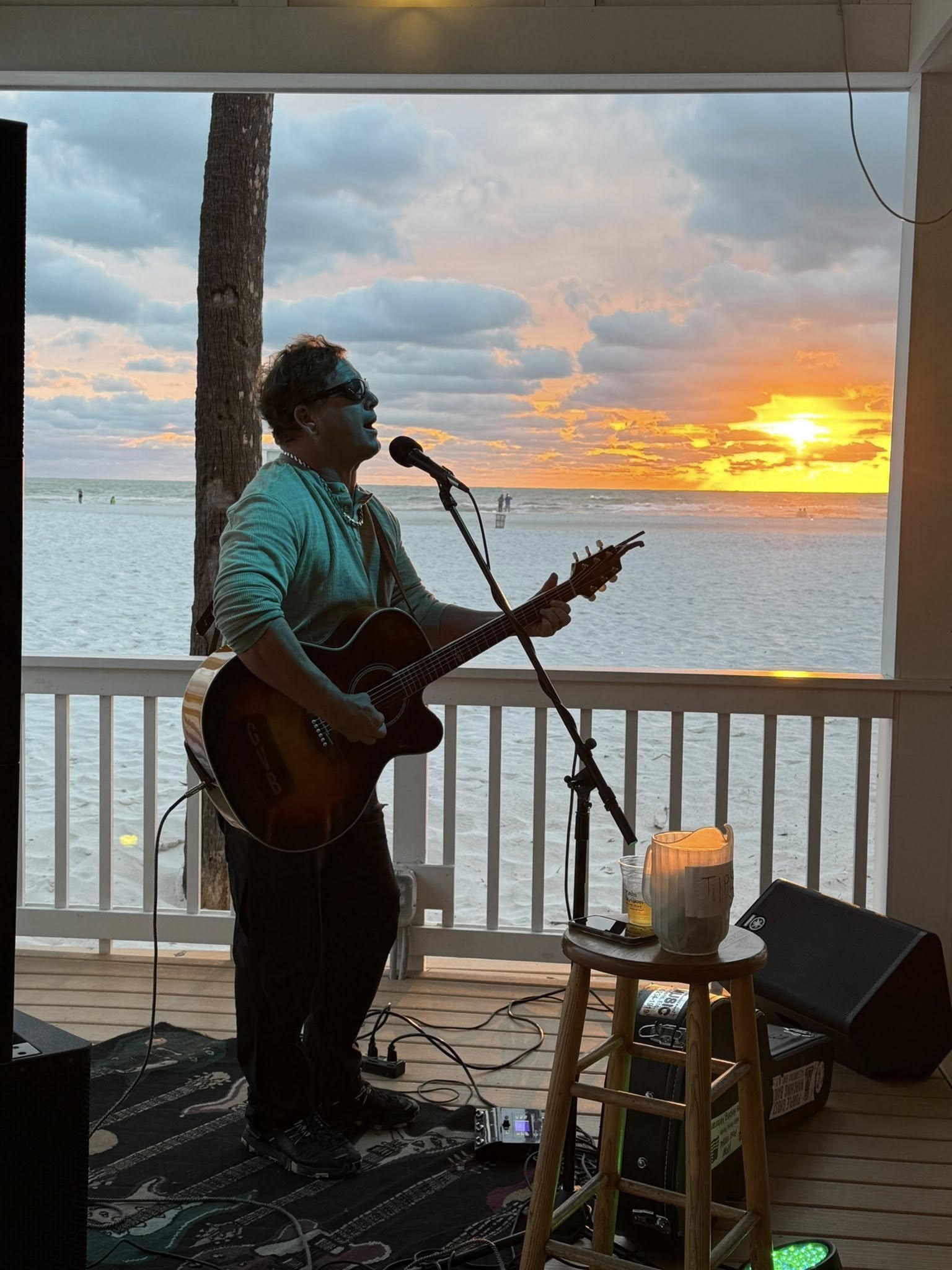 Gary Van Brocklin Live May 23, 2025: A musician performing at an outdoor tiki bar by the water at night.