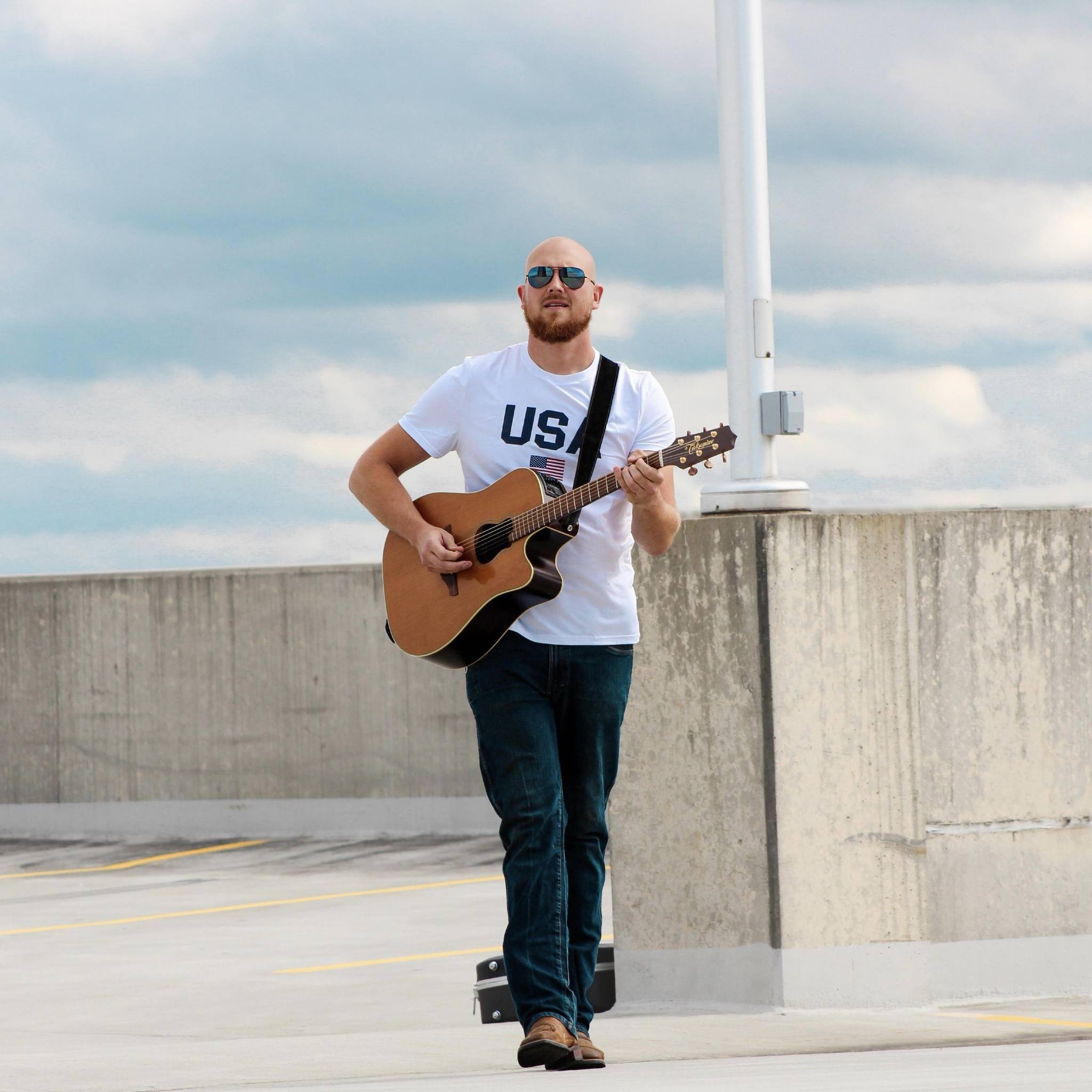 Josh Breen live performance at an outdoor tiki bar in 2025, with a vibrant crowd enjoying the music by the water.