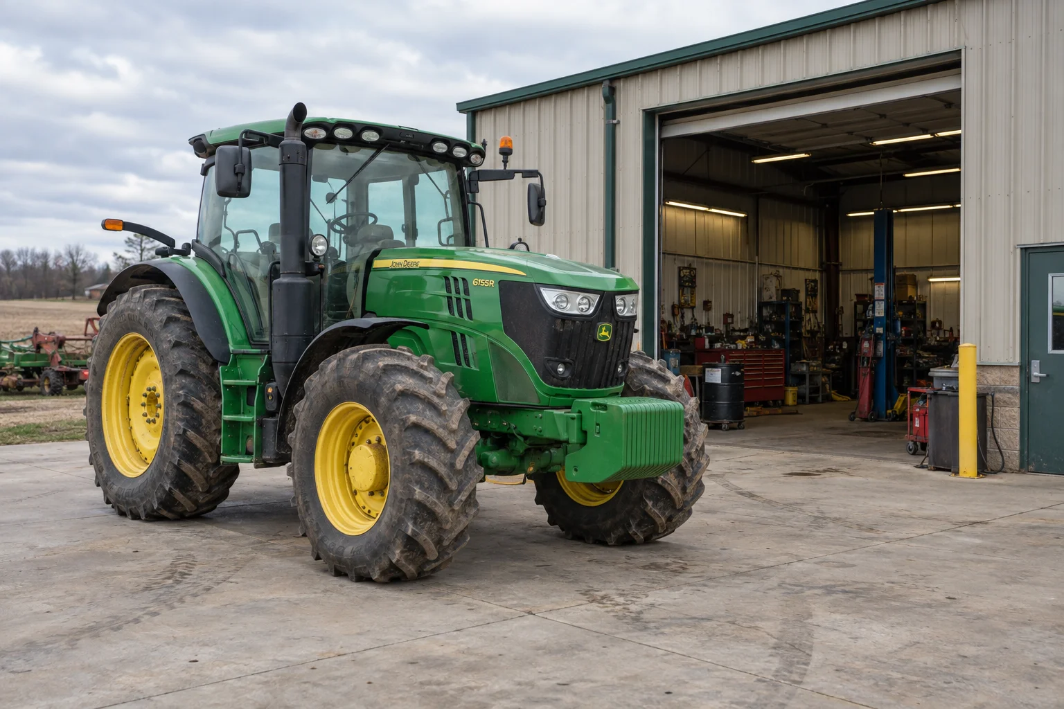 Green tractor parked outside an agricultural equipment repair workshop.