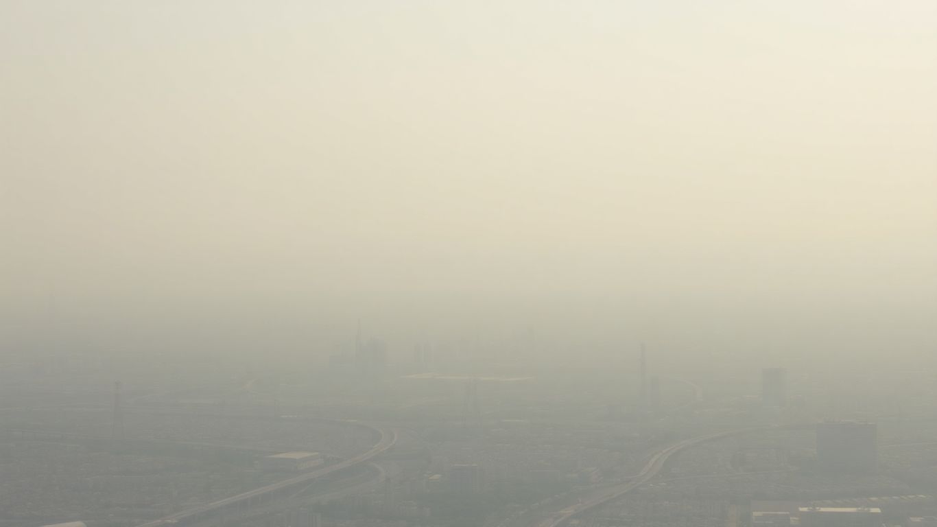 Cityscape with industrial and transportation elements under a hazy sky.