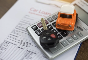a car loan note and a calculator with a key and toy car