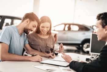 a couple signing the paperwork to buy a car