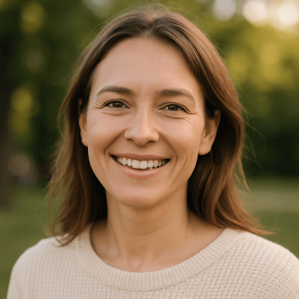 A smiling woman with natural, healthy-looking skin standing outdoors in soft sunlight, representing wellness and confidence.