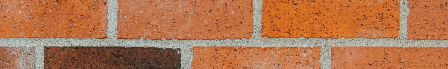 Mur en briques rouges avec texture variée, mettant en avant des travaux de maçonnerie traditionnelle.