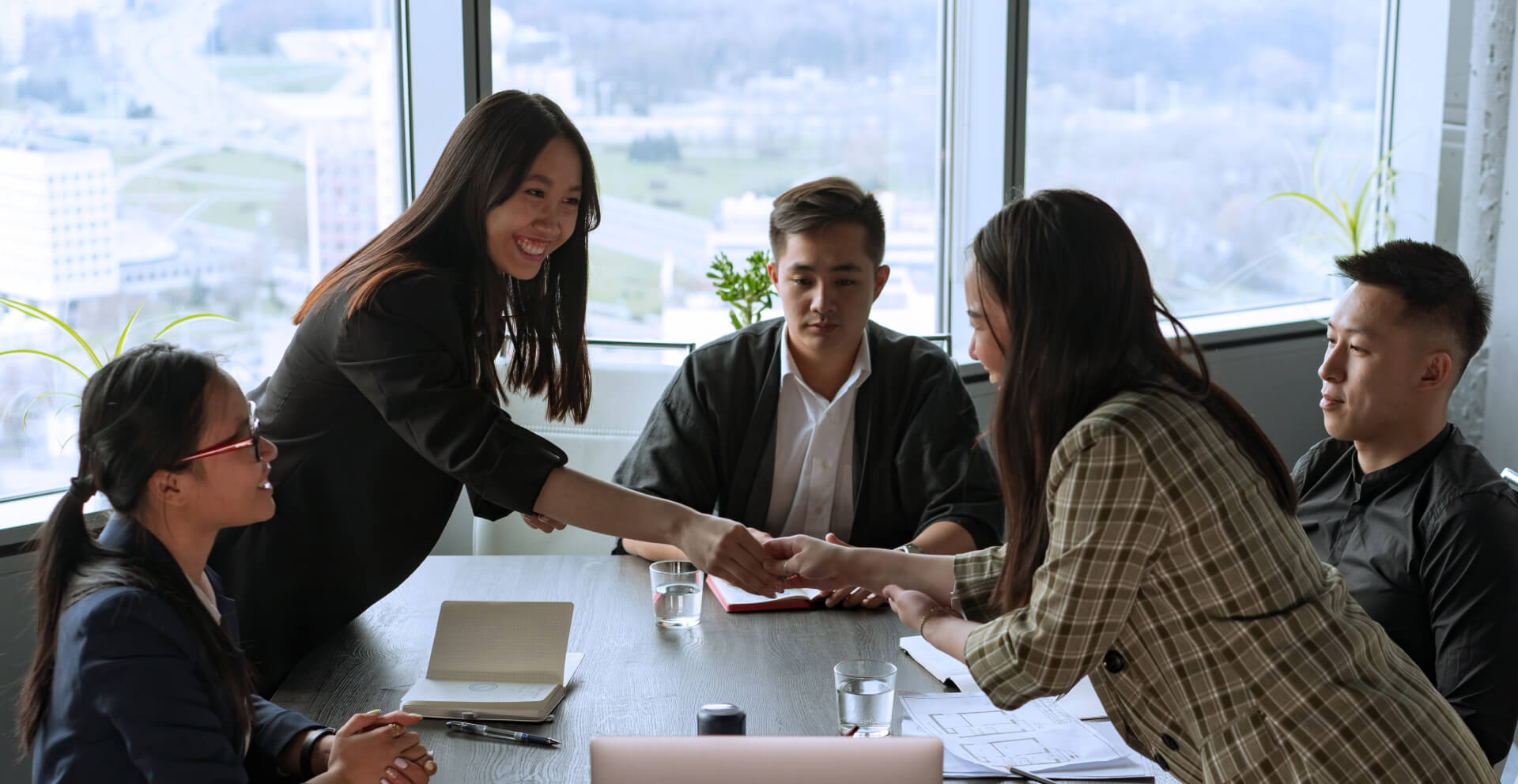 a group of people sitting around a table shaking hands