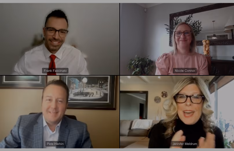 Video call showing four people: a man in a white shirt and red tie, a woman in glasses and a pink blouse, a man in a gray checked jacket, and a woman in glasses with curled blonde hair speaking.