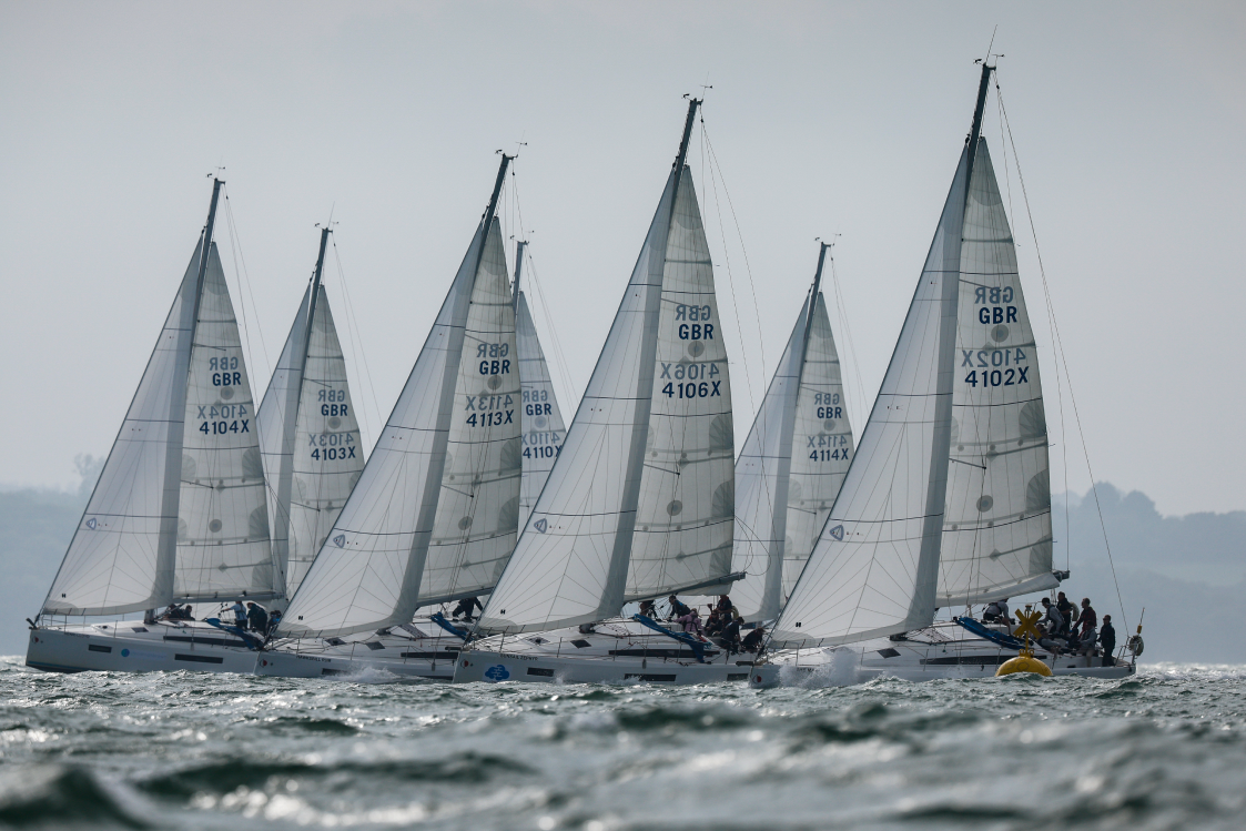 A fleet of yachts lined up at the start of a race