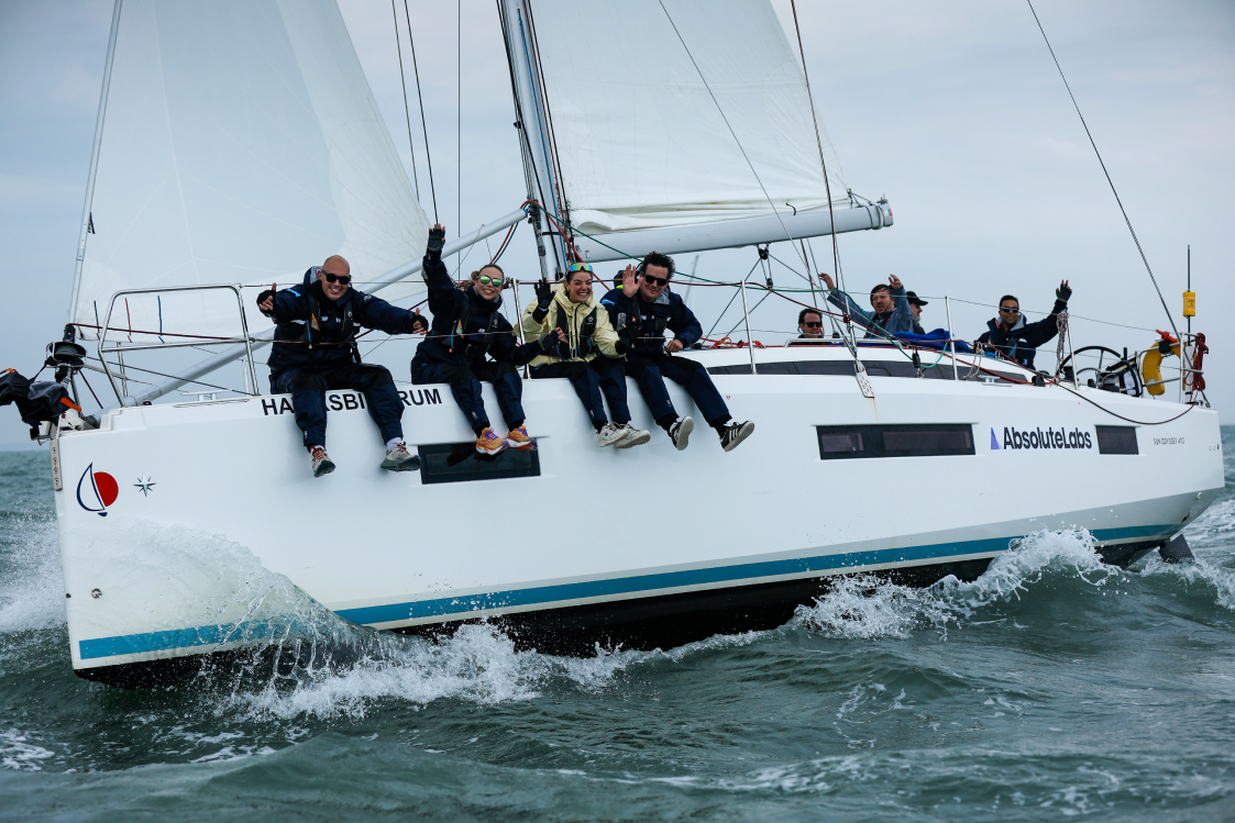 The crew sitting along the side of the boat as it cuts through the water