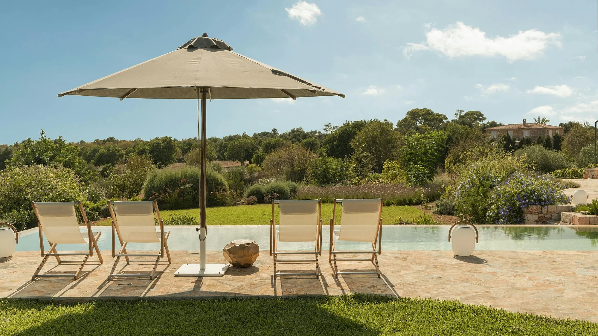 Sun loungers by the pool at ByMilagro luxury villa in Mallorca surrounded by Mediterranean gardens