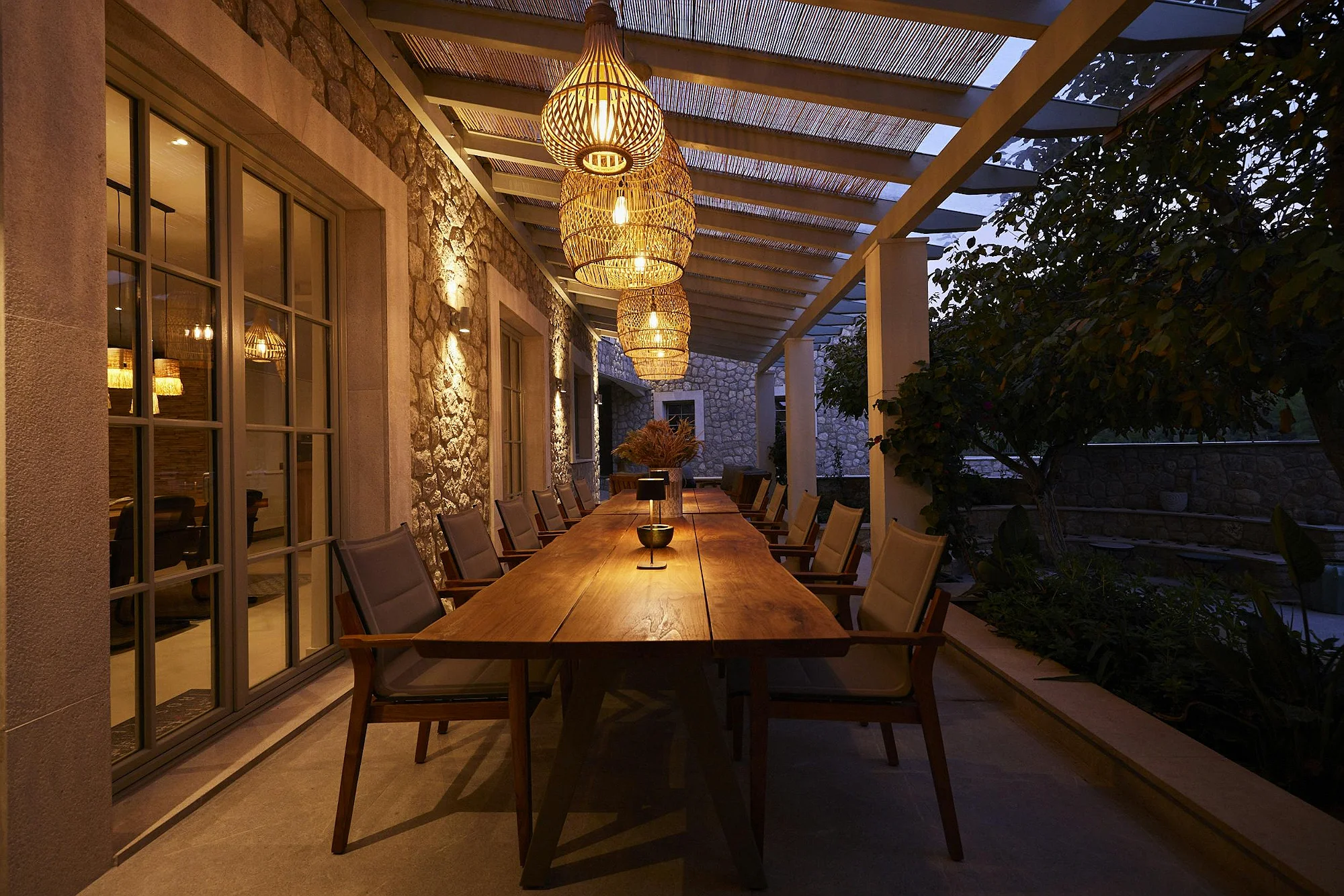 Long outdoor dining table under pergola with lanterns at ByMilagro luxury holiday villa Mallorca