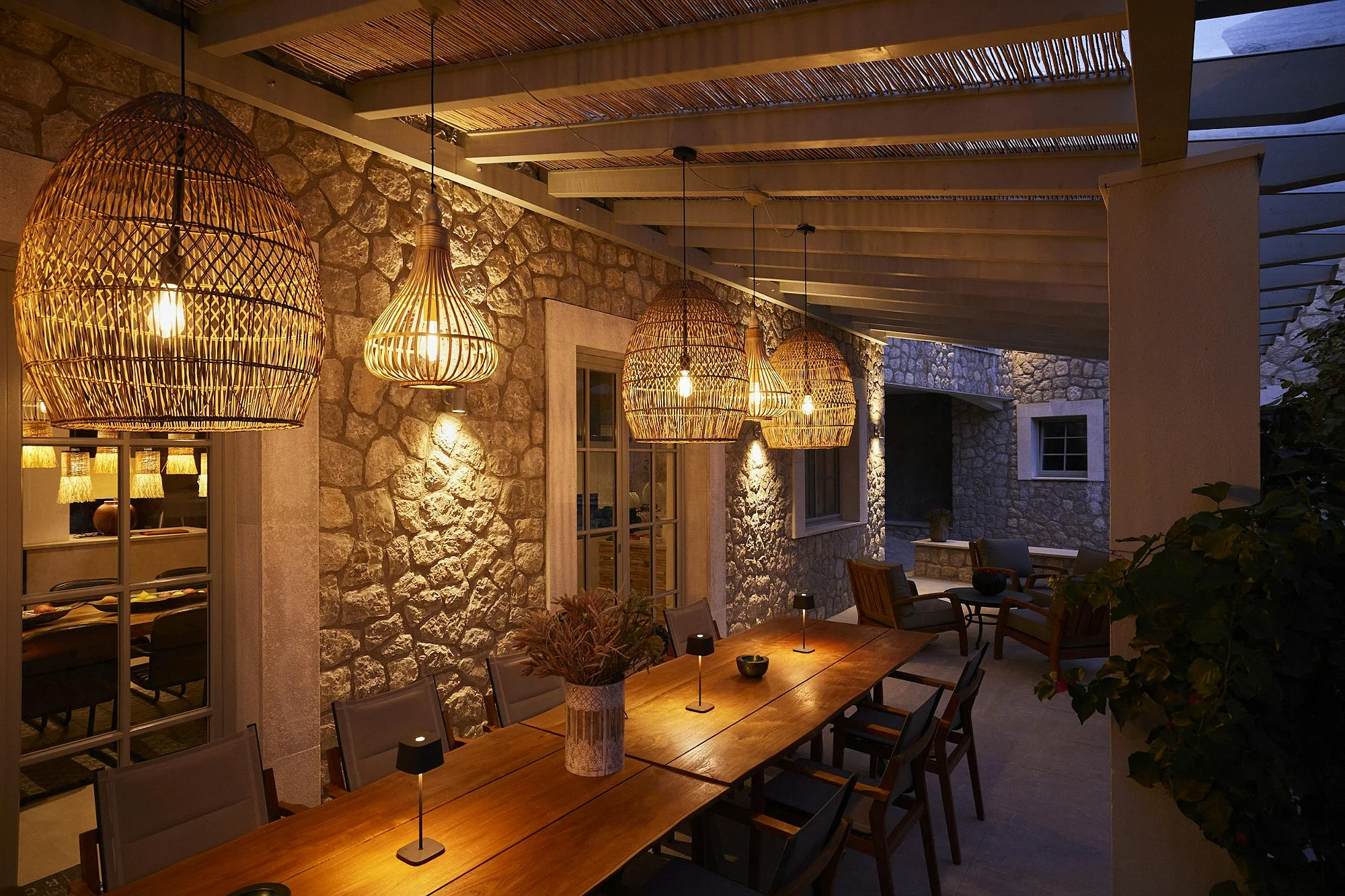 Covered terrace with rustic stone walls and rattan lamps at ByMilagro villa rental Mallorca