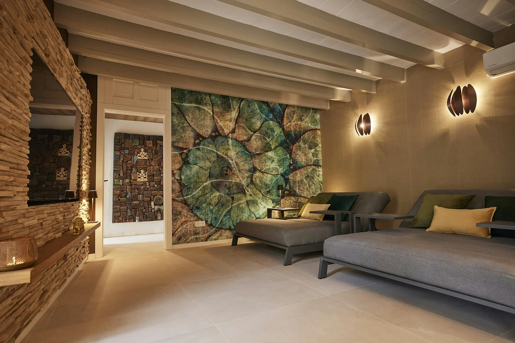 Living room with chaises longues, stone walls, exposed beam ceilings, and artistic wallpaper.