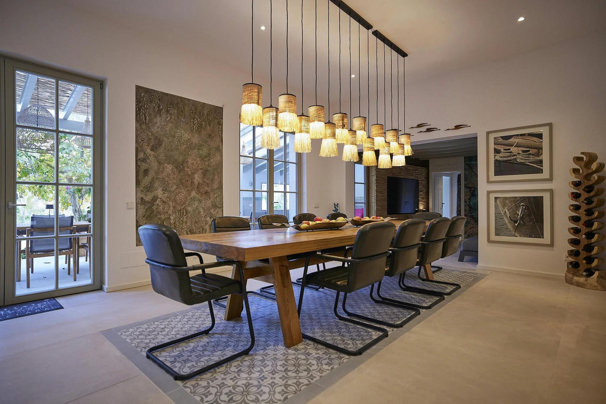 ByMilagro luxury dining room with large wooden table, black leather chairs, hanging lamps, and elegant interior design in a rental property.