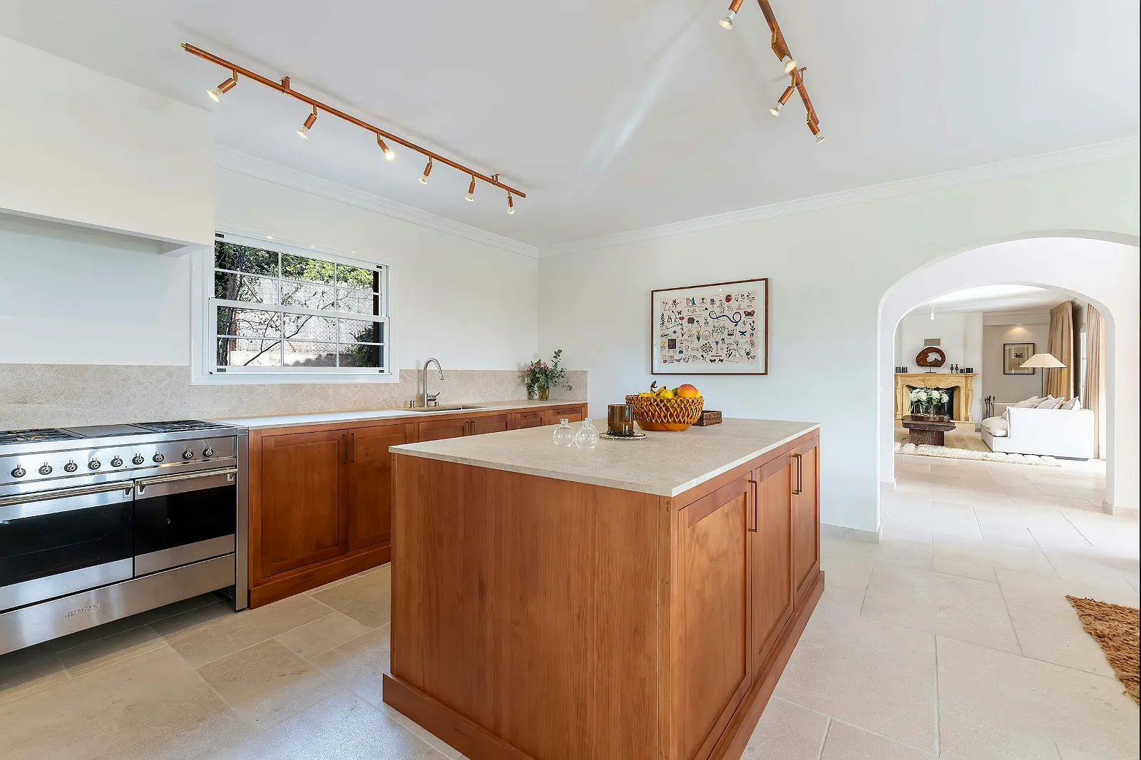 Spacious kitchen at Villa Scarlett with wooden island, professional-grade range, track lighting, and archway leading to the living room. ByMilagro rental.