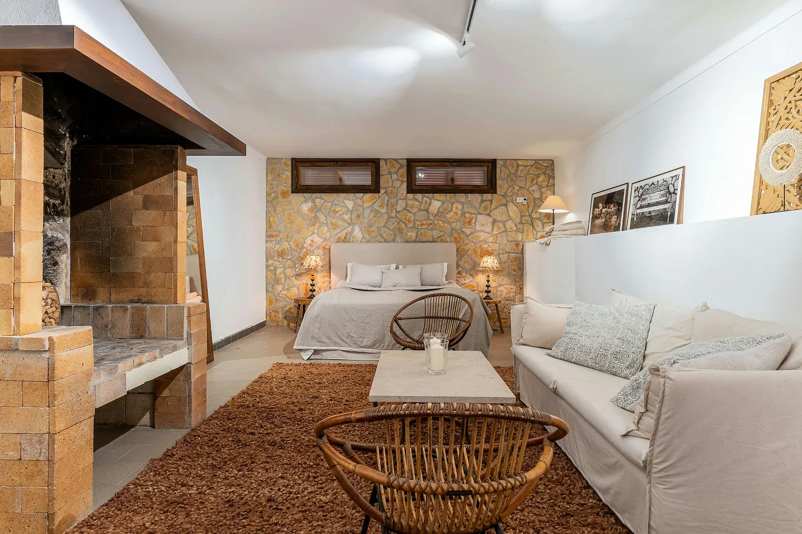 Rustic-chic bedroom suite at Villa Scarlett with exposed stone wall, sitting area, and built-in indoor BBQ/fireplace. Unique luxury rental ByMilagro.