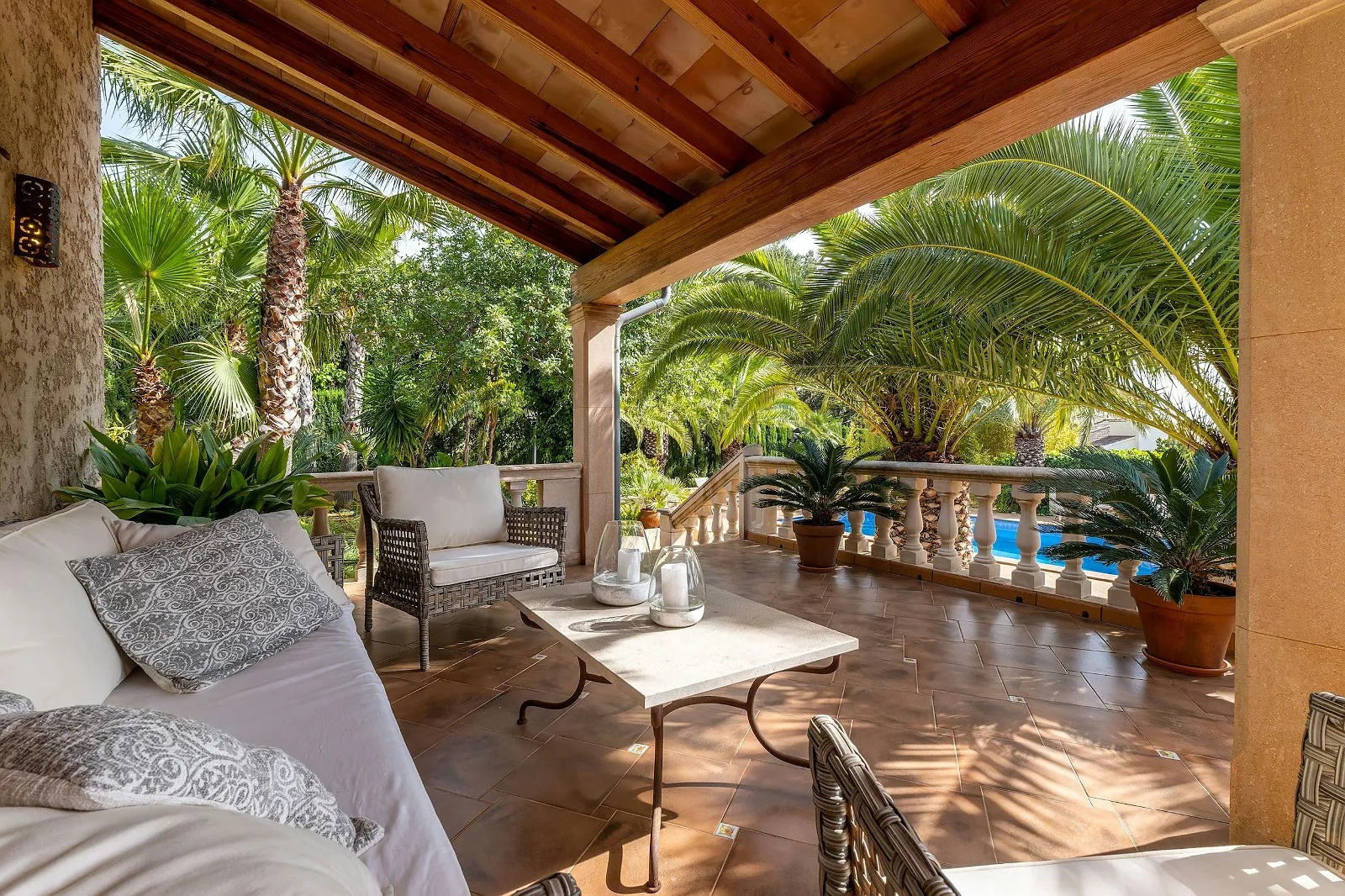 Covered seating on the upper balcony overlooking the tropical garden and pool area at Villa Scarlett, emphasizing the luxury outdoor living of ByMilagro.