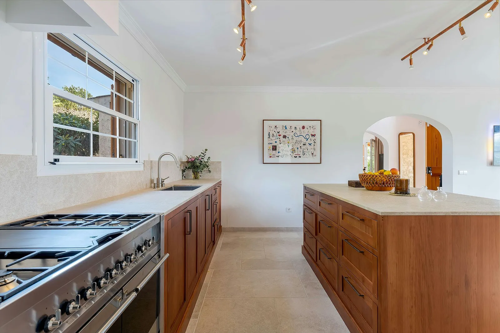 Kitchen view in Villa Scarlett showing the stainless steel stove, wooden cabinetry, and sink area with natural light. Luxury rental property ByMilagro.