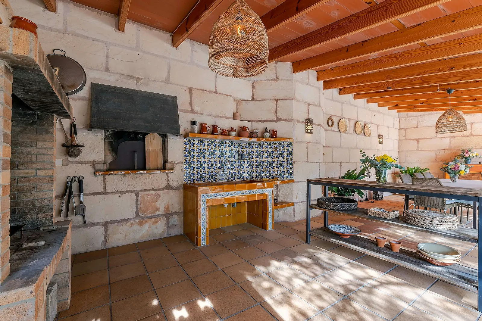 Traditional outdoor kitchen and BBQ area at Villa Scarlett with stone walls, tiled backsplash, and cooking hearth. Perfect for entertaining at ByMilagro.