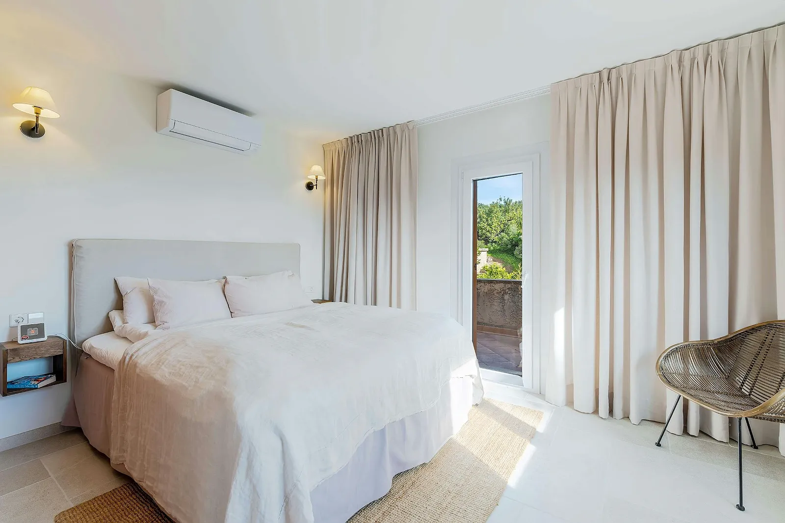 Minimalist white bedroom in Villa Scarlett with a plush bed, large curtains, and direct access to a private balcony. ByMilagro luxury rental.