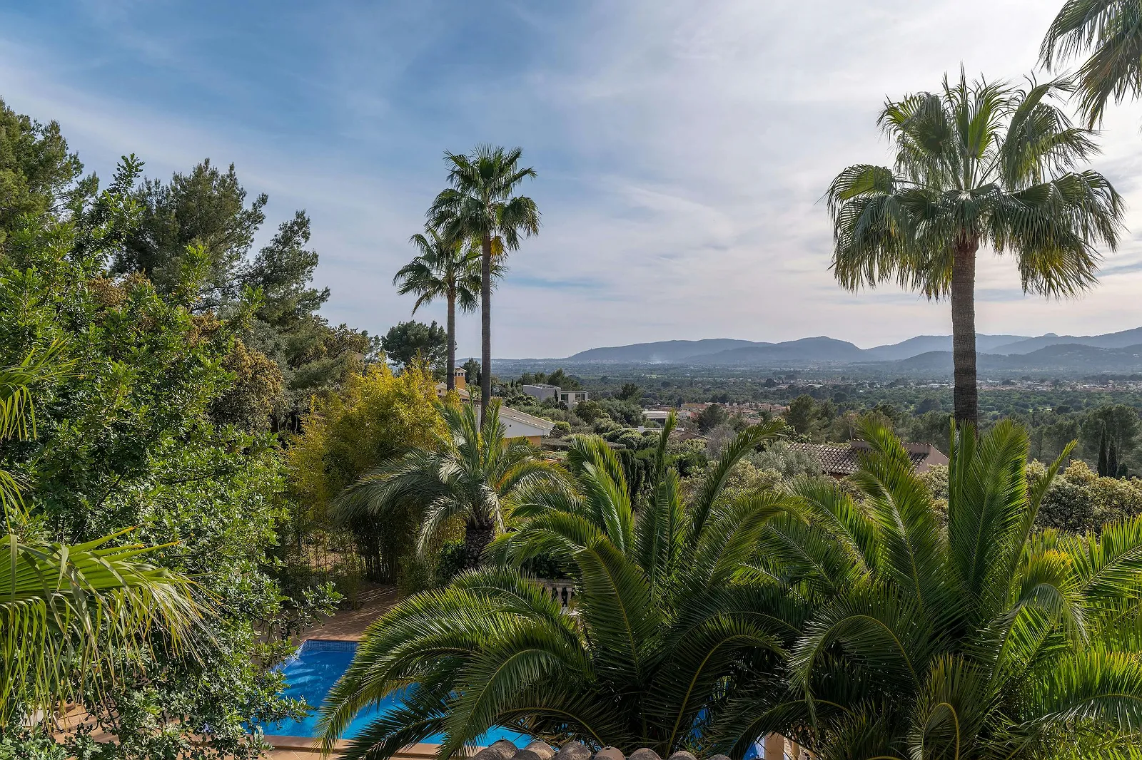 Panoramic mountain and valley view from Villa Scarlett balcony, showing the pool and surrounding palm trees. Luxury view rental ByMilagro.