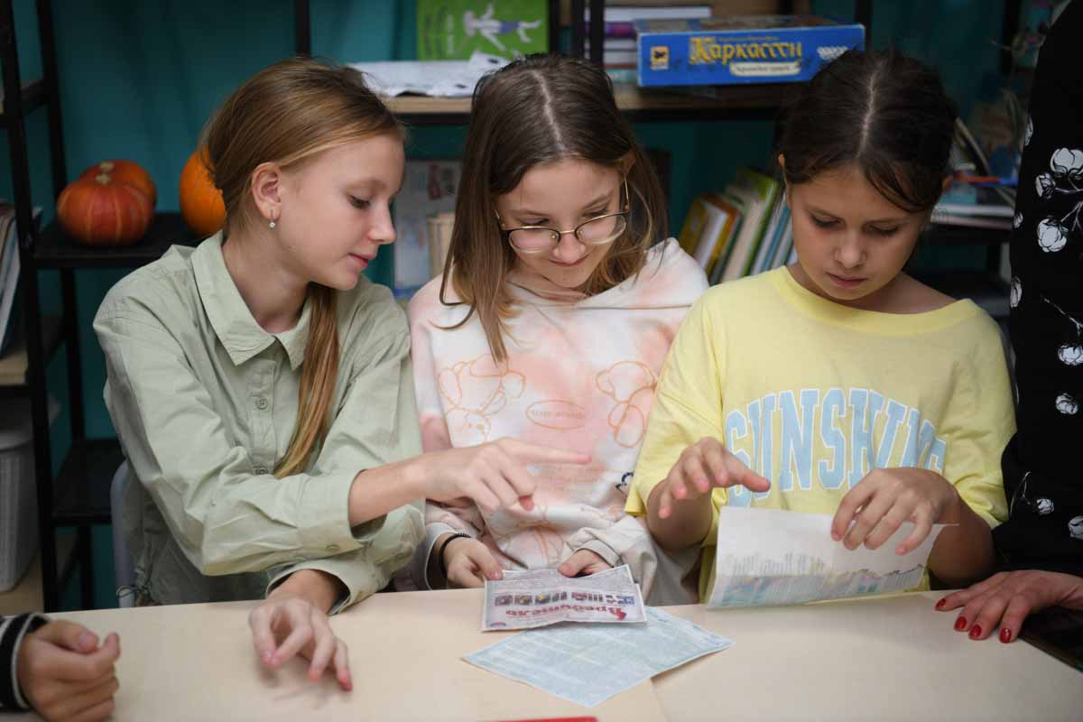 Три учениці середньої школи створюють настінну газету до дня Т. Г. Швеченка