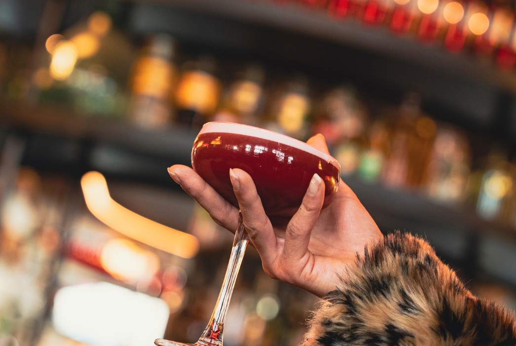 mains qui tiens un cocktail devant le bar central