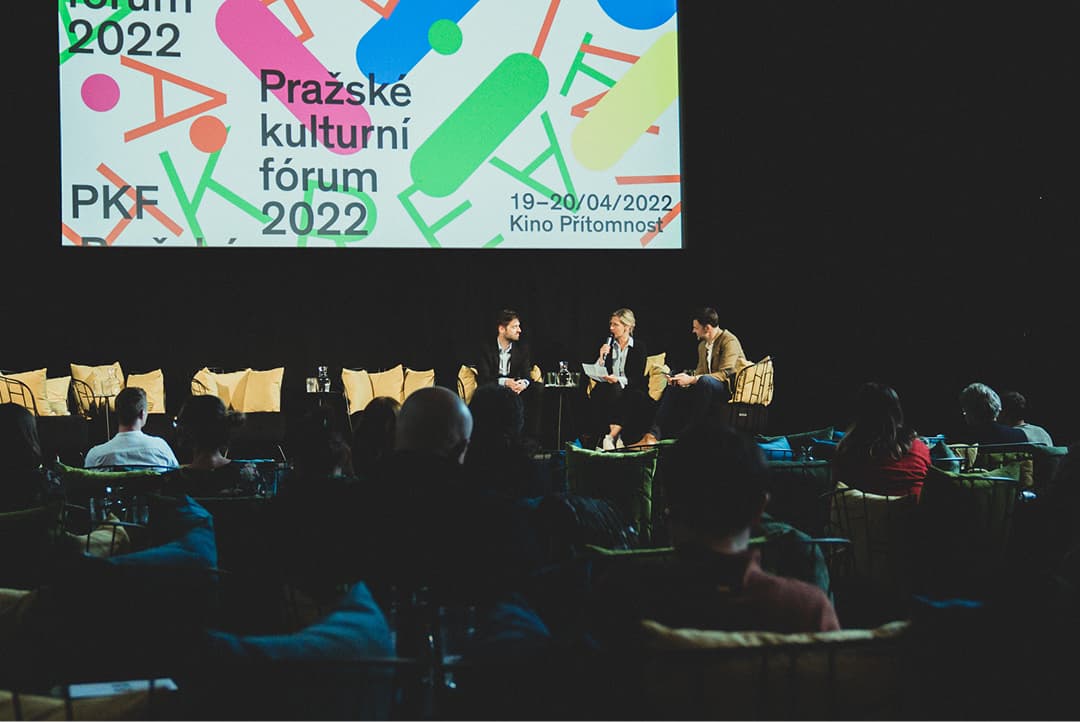 Panelová diskuse na Pražském kulturním fóru 2022 se třemi řečníky sedícími na pódiu a publikem před nimi.