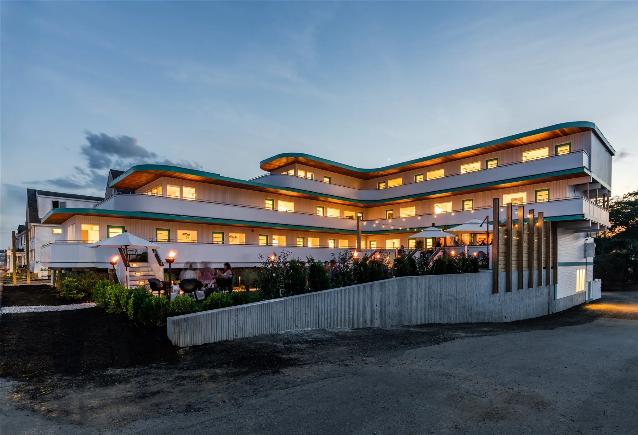 The Nevada Hotel building at nighttime. The building stands out with mid-century style, with curved corners and teal trim.