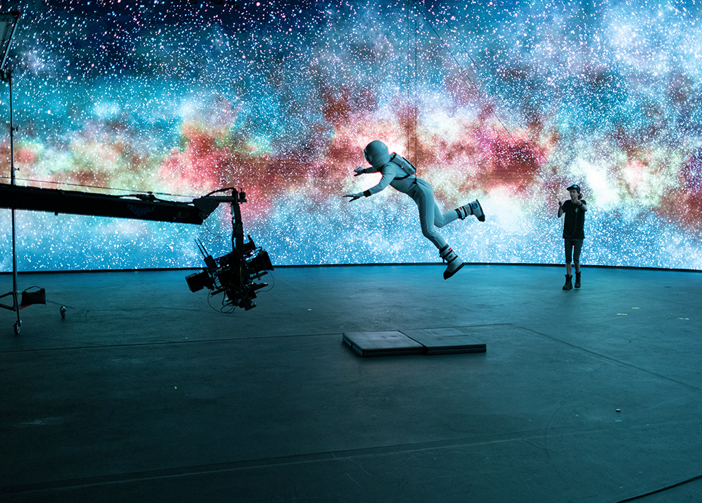 a person jumping in the air in front of a wall with a picture of a