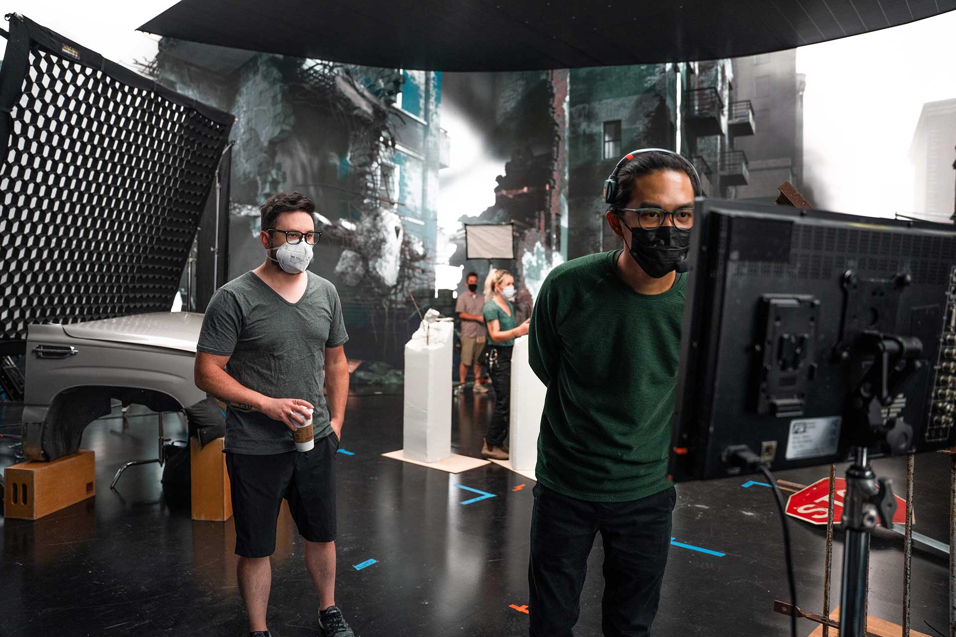 Vū team wearing face masks. Tech person standing in front of a screen.