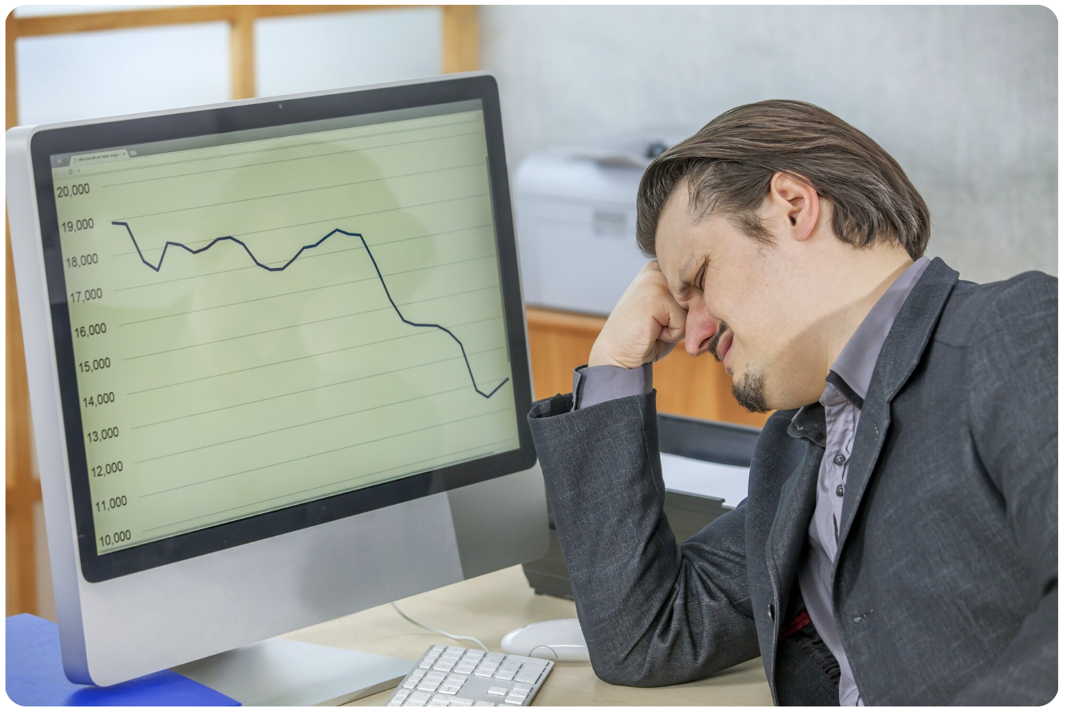 A business professional sits at a desk with financial documents and charts spread out, showing declining revenue trends and missed leads for the quarter. 