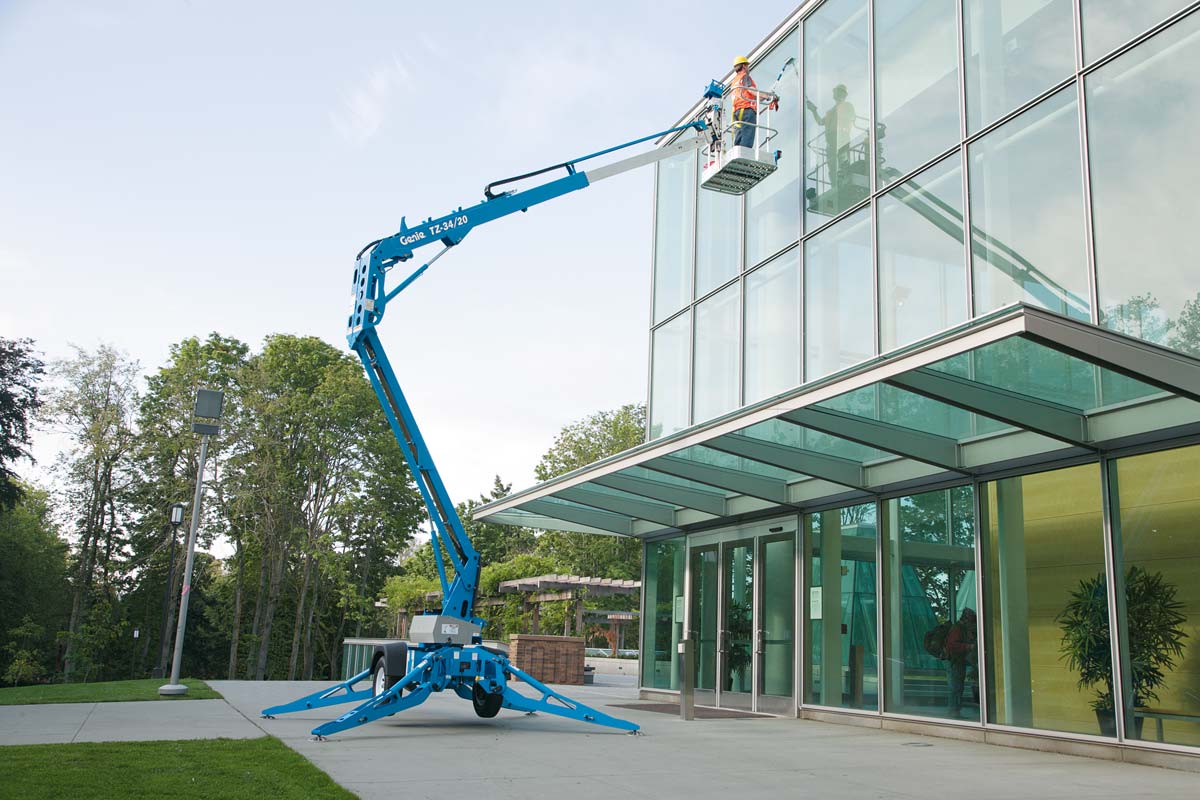 Genie TZ-34/20 towable boom lift working on a commercial building — no CDL required, available at Northside Tool Rental