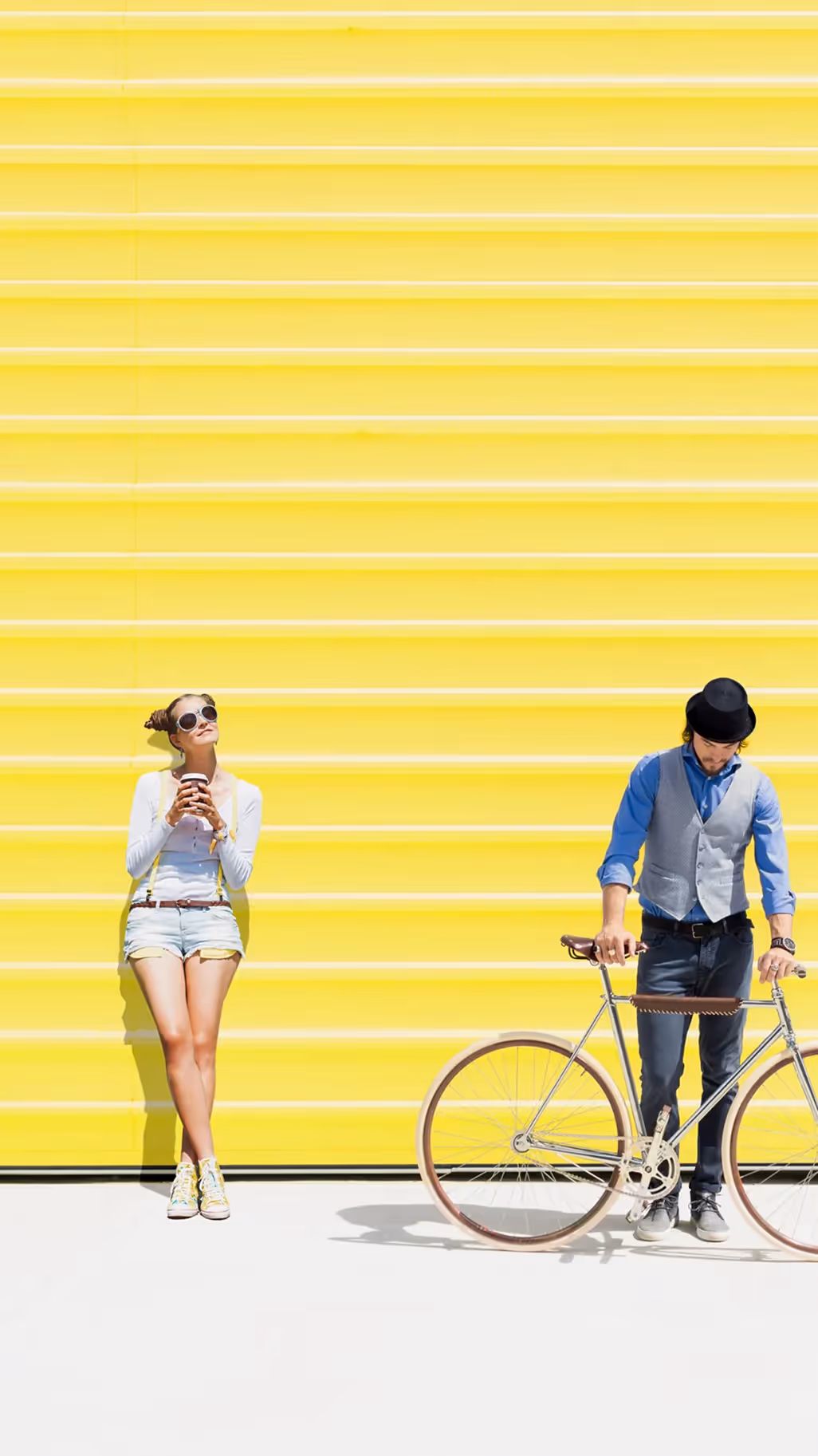 Frau und Mann mit einem Fahrrad vor einer gelben Wand. Yellowshark – Werbeagentur Zürich
