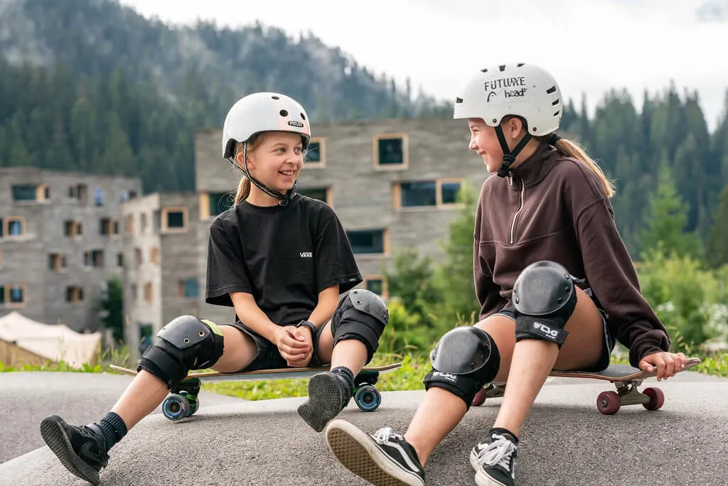Zwei Kinder mit Skateboards & Schutzausrüstung bei Familienferien in LAAX