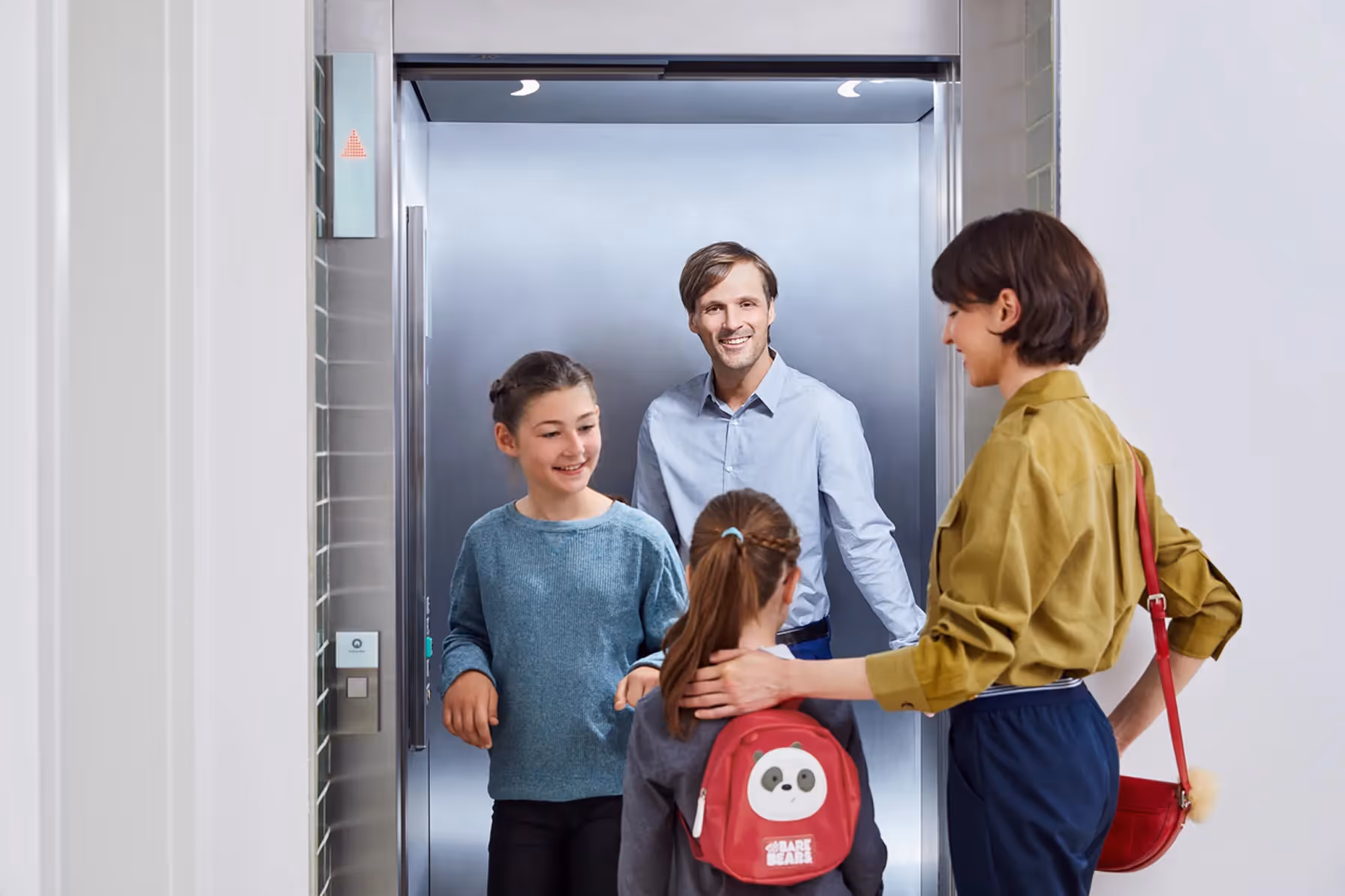 Familie vor modernem Personenaufzug von Schindler in einem Wohngebäude